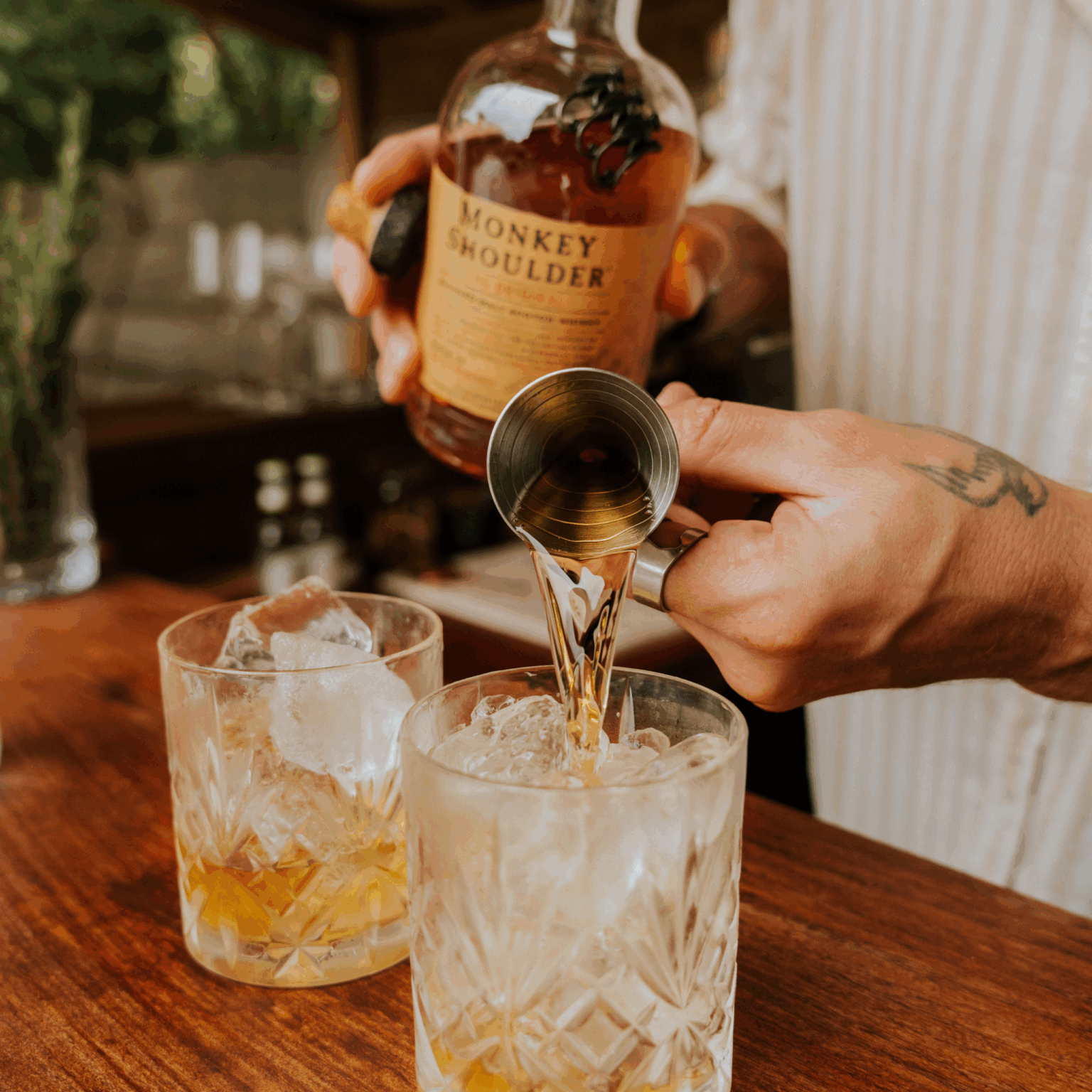 Verse du whisky Monkey Shoulder dans un verre lowball rempli de glaçon pour un Monkey Tonic avec Hysope