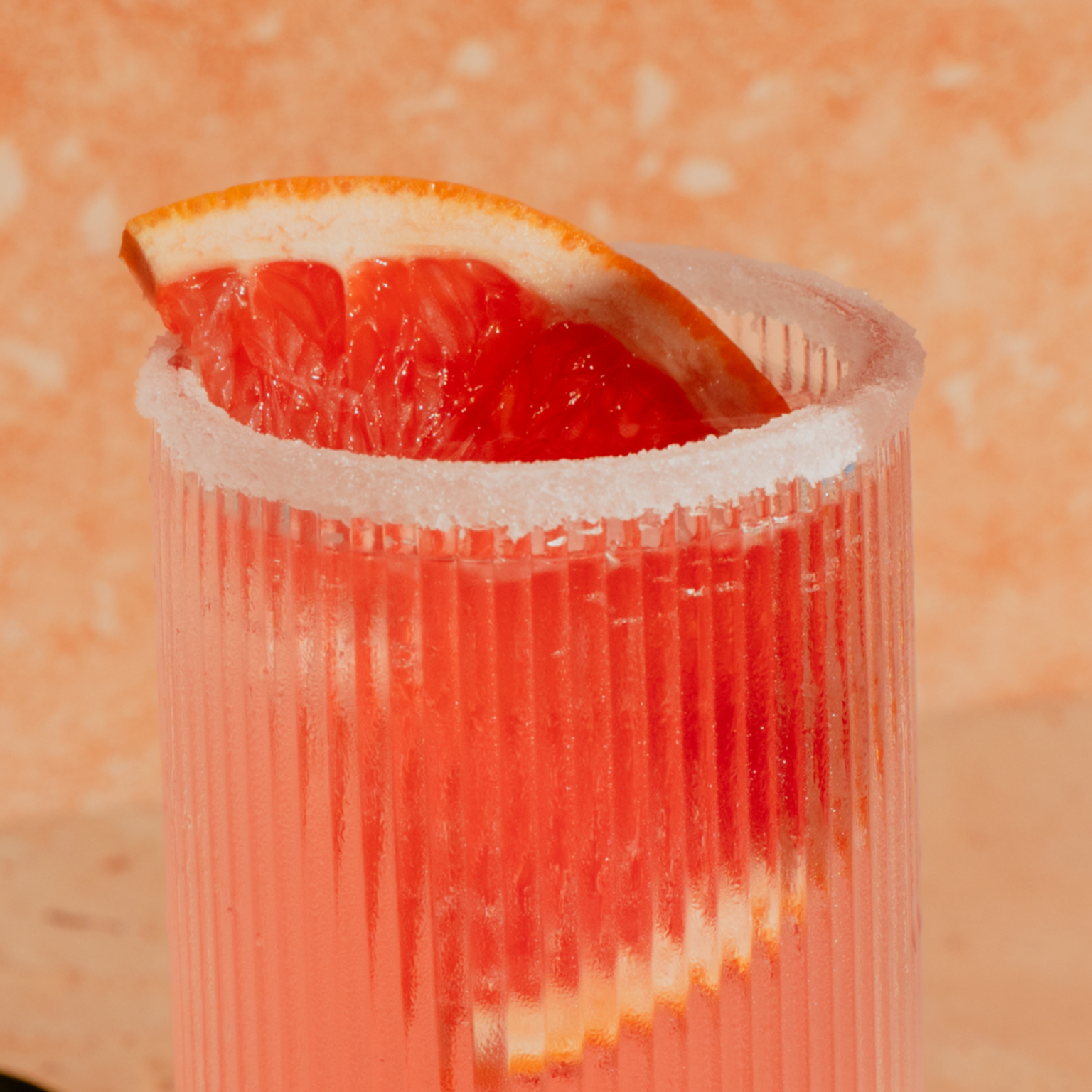 Verre Highball de cocktail Paloma rose givré au sel avec une tranche de pamplemousse rose