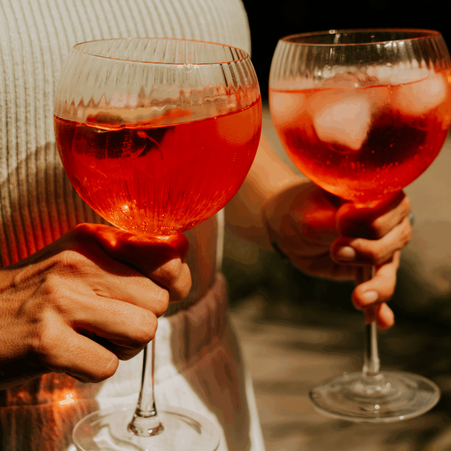 Verres de Campari Tonic Hysope dans des mains, cocktail rouge éclatant